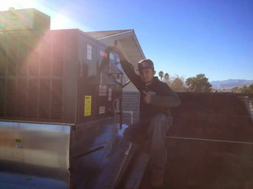 HVAC technician performing Heat Pump Repair on a rooftop unit in Evans